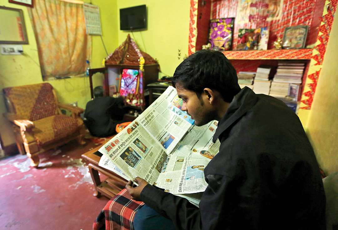 Rewatiraman Shukla, 24, reads his morning newspaper in his house in New Delhi, India.